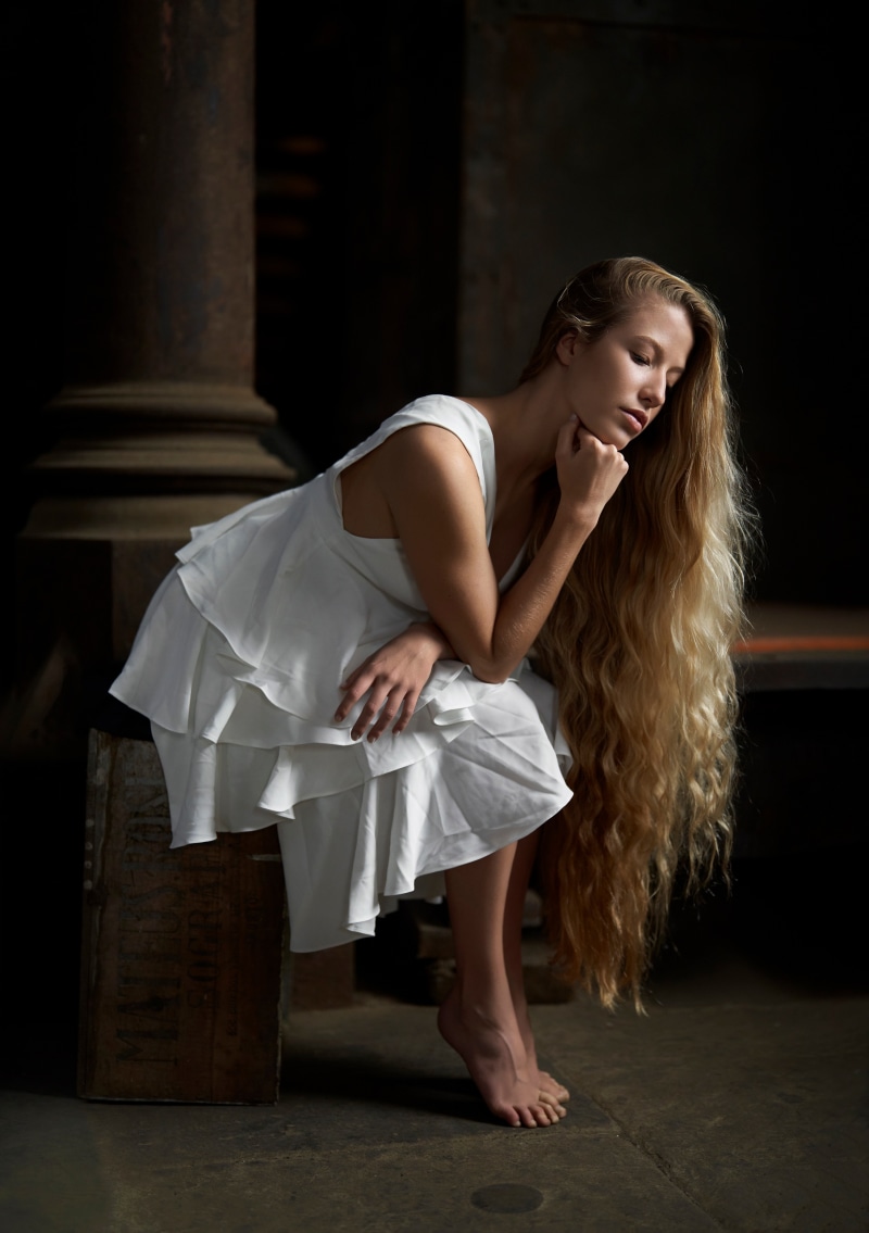 Blonde woman in white dress sitting
