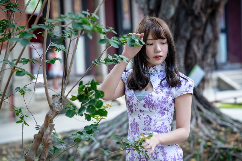 Asian woman in a floral dress near a tree