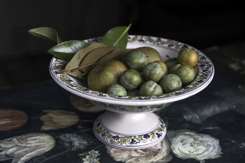 Fruit bowl with plums, apples, and leaves