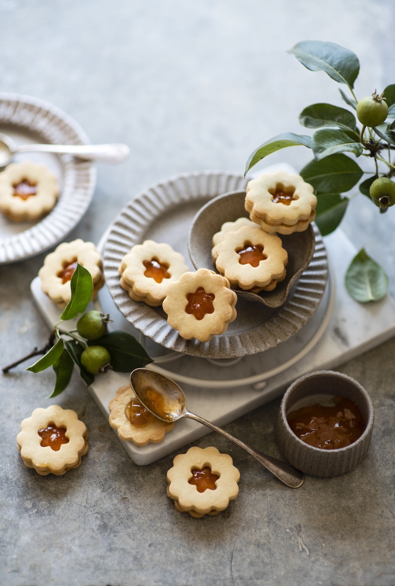 Linzer cookies with jam on plates and a spoon