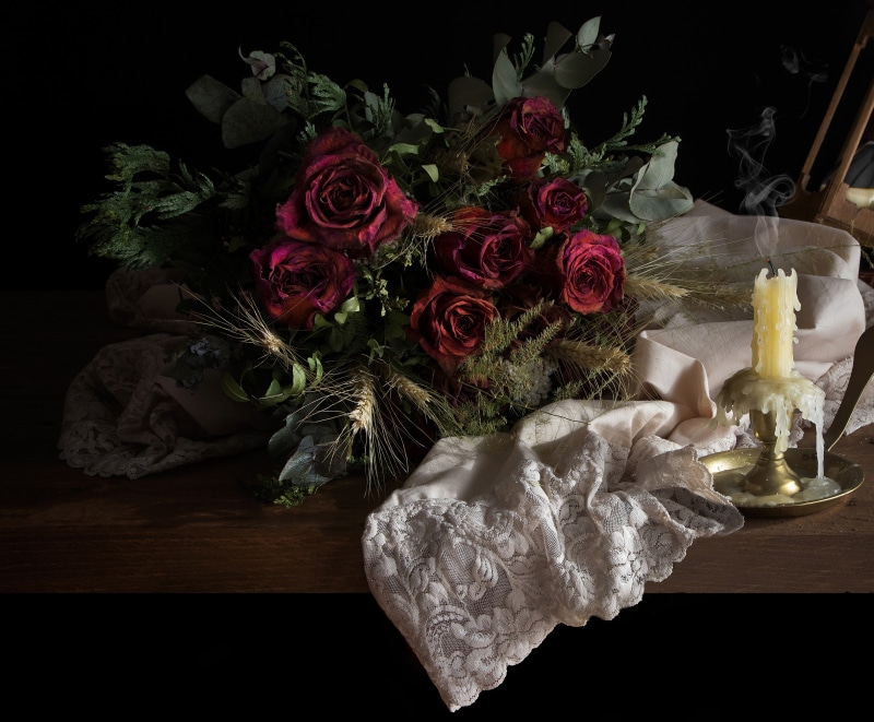 Still-life of dried roses and a lit candle