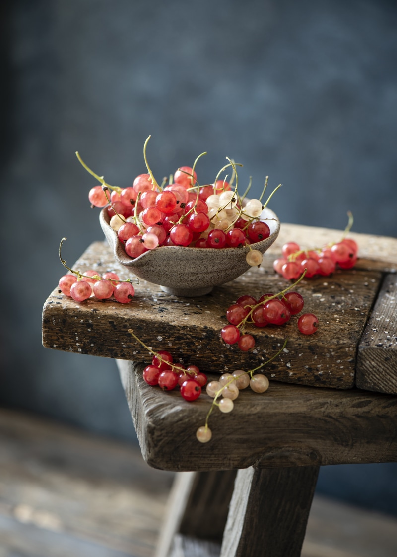 Red and white currants in a bowl on a wooden surface
