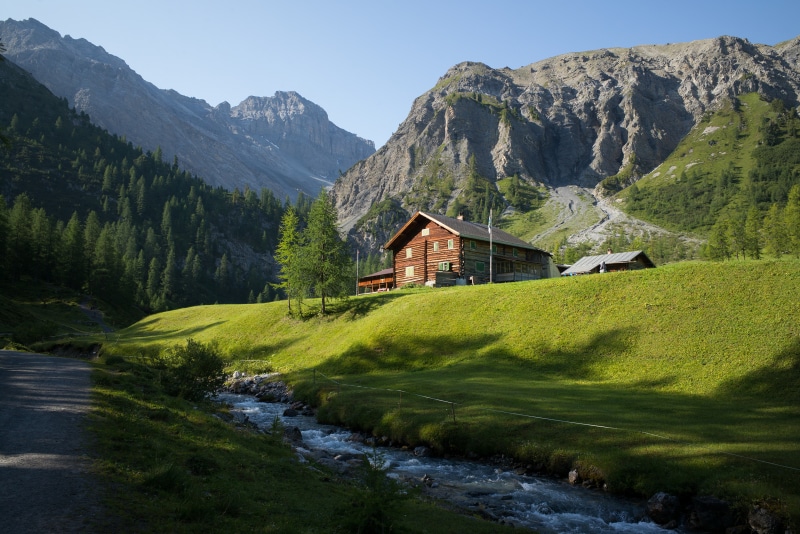 Log cabin houses in the Swiss Alps with mountains and stream