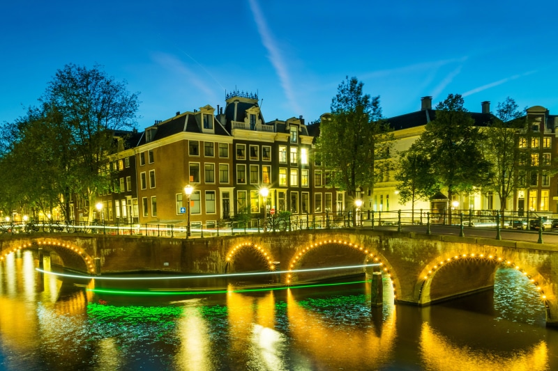 Amsterdam canal bridge at night with illuminated houses