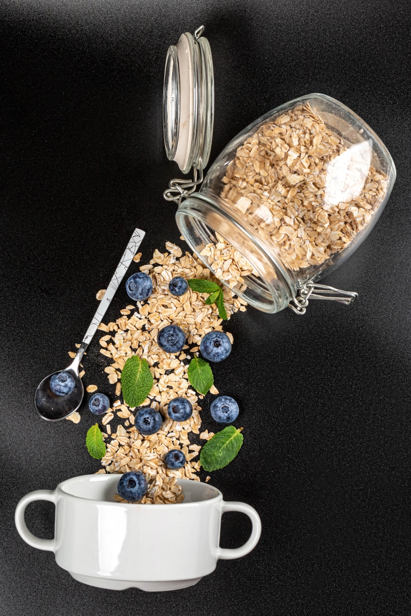 Oatmeal and blueberries spilling from a jar into a bowl
