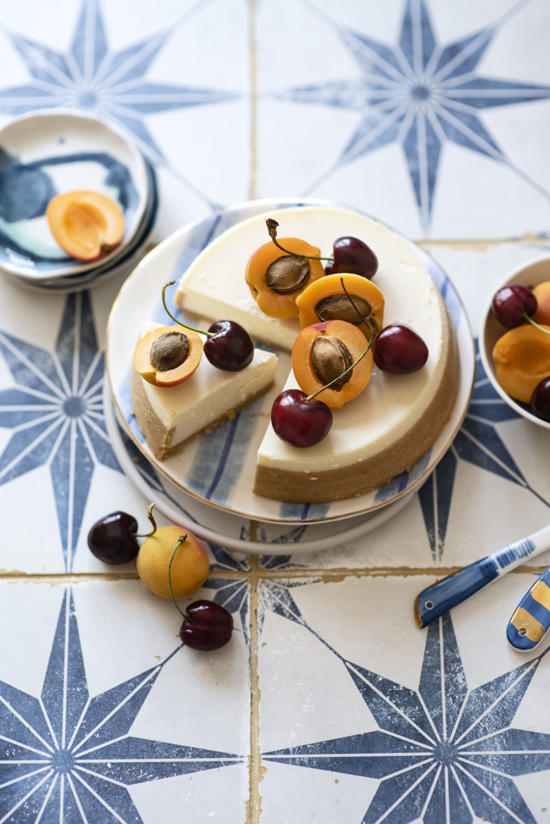 Cheesecake with apricots and cherries on a decorative tile surface