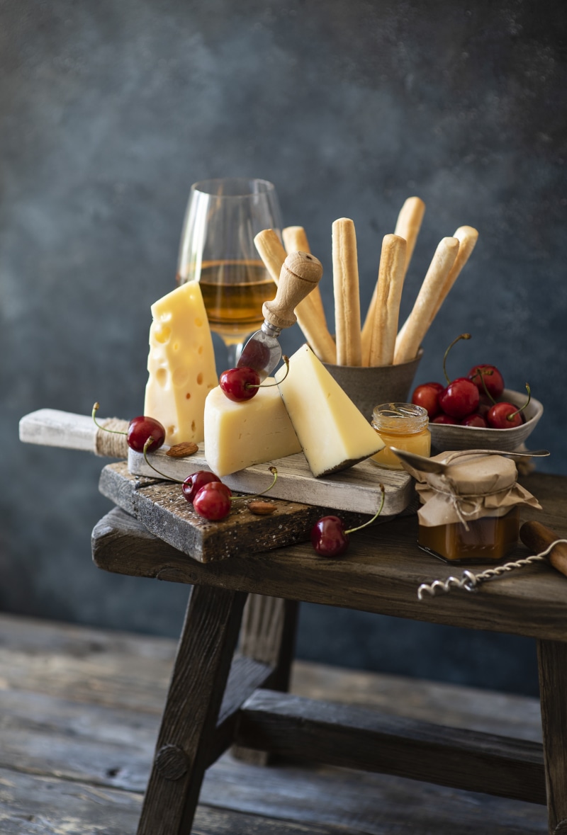 Still life of cheese, cherries, wine, and breadsticks