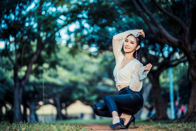 Asian woman in white blouse and black trousers posing