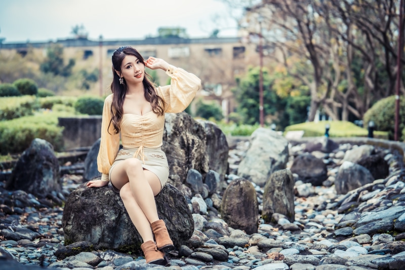Asian woman sitting on rocks in a park