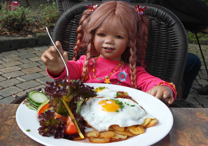 Doll eating breakfast with fried eggs and salad