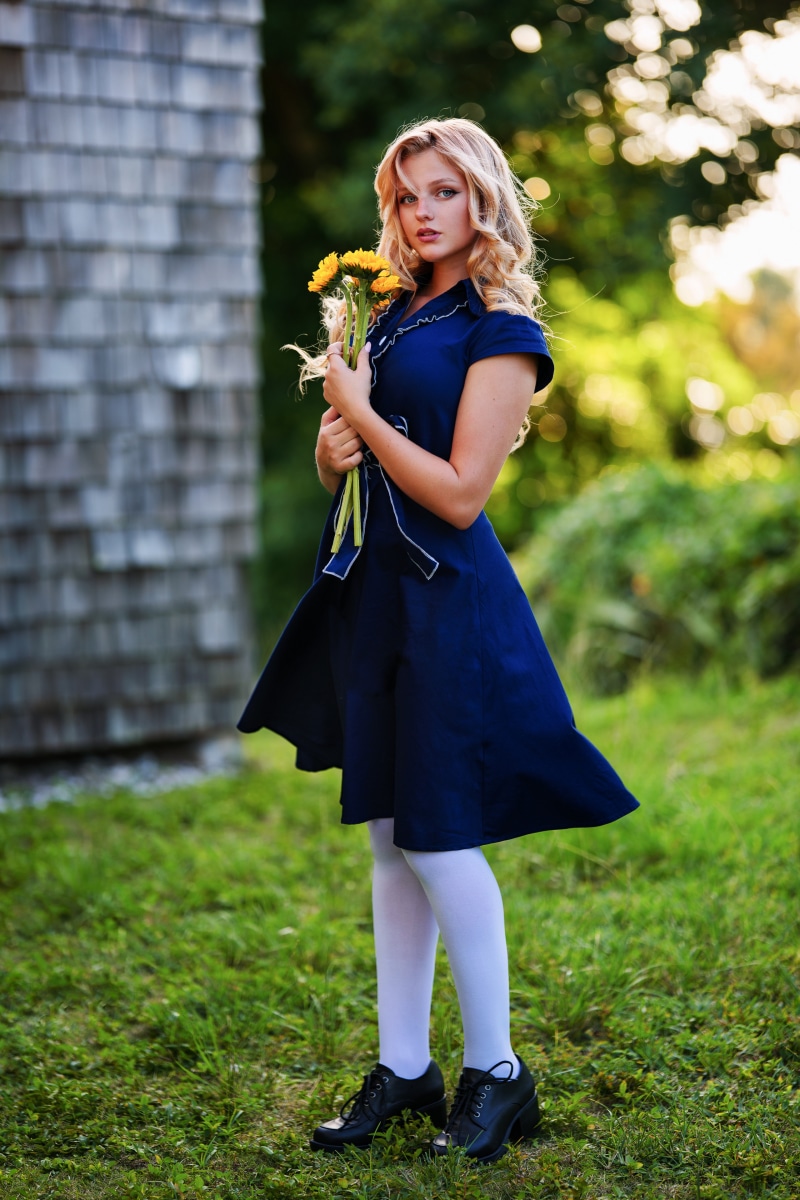 Hannah holding yellow flowers in a blue dress