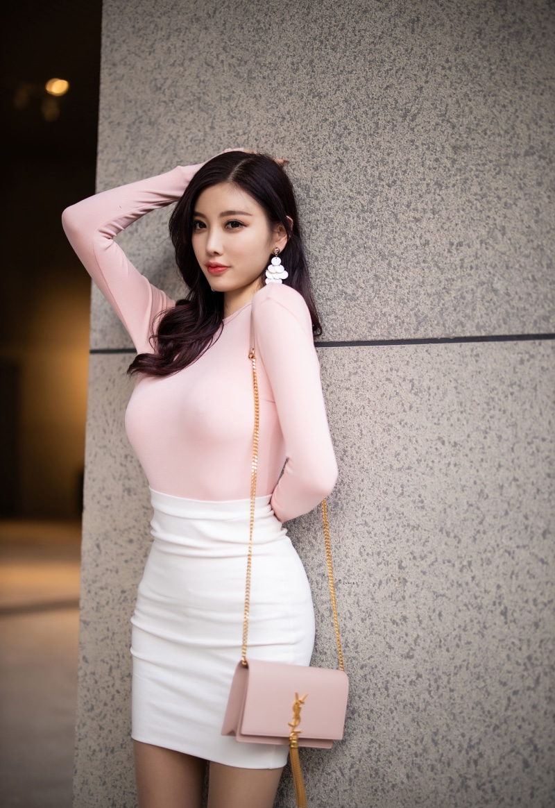 Asian woman in pink top and white skirt with handbag