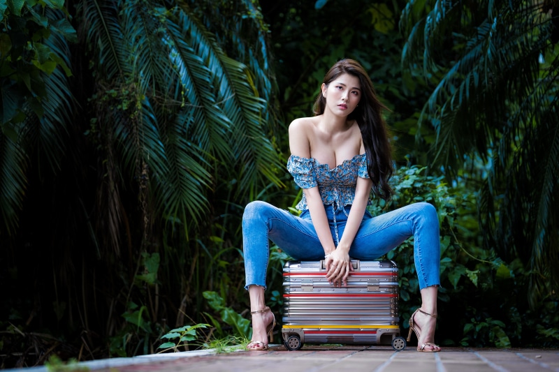 Asian woman sitting on a suitcase