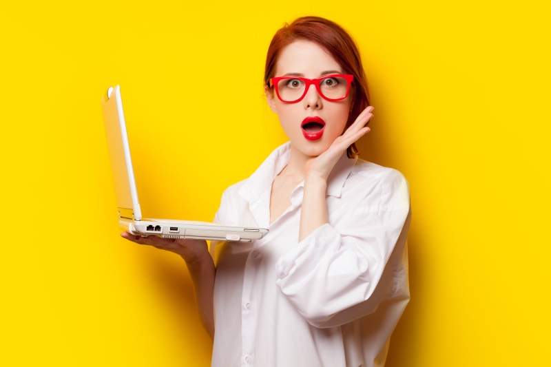 Redhead girl with red glasses holding a laptop