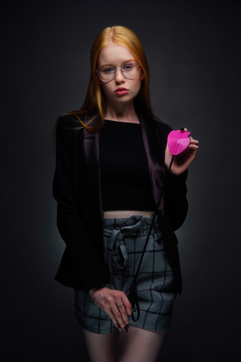 Redhead girl with glasses holding a pink heart-shaped object