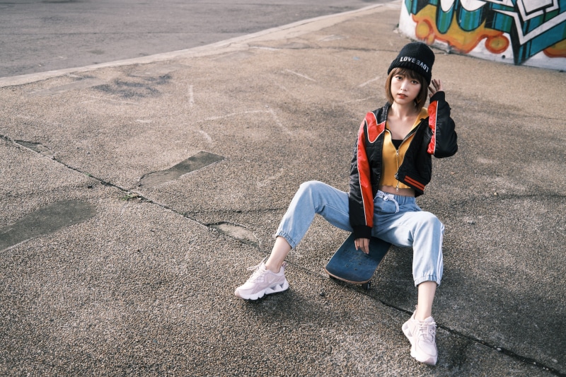 Asian woman in winter hat sitting on skateboard