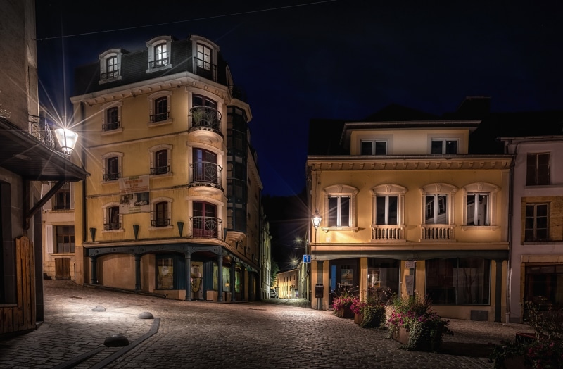 Cobblestone street at night with illuminated buildings and streetlights