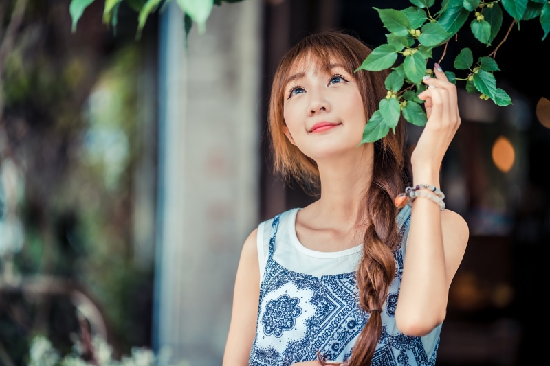 Asian woman with braid hair under branches