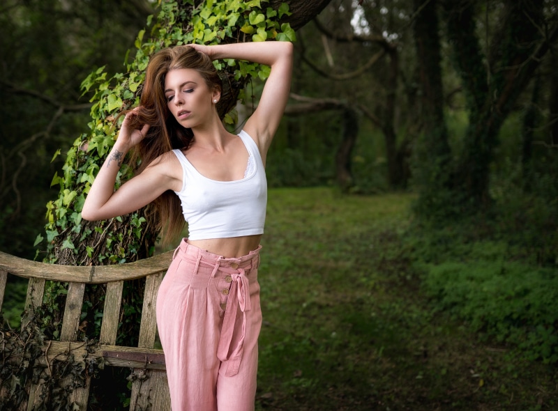 Woman in white crop top and pink pants posing in a forest