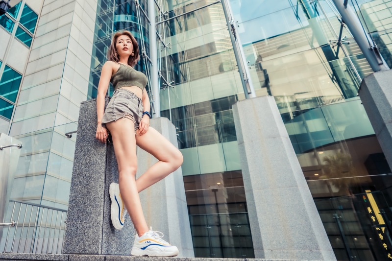 Asian woman in athletic wear posing near modern building
