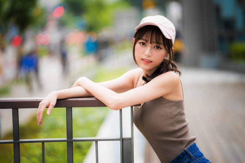 Asian girl with baseball cap leaning on railing