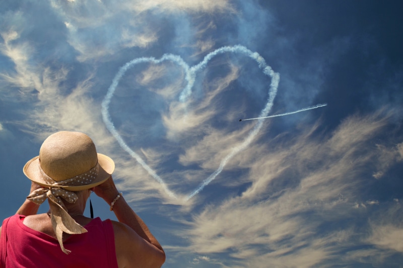 Woman watches plane draw heart in sky