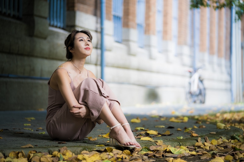 Asian woman sitting on the ground with foliage