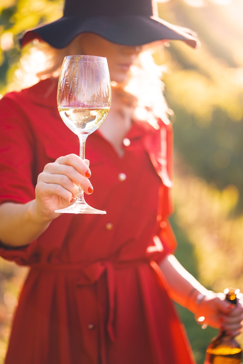 Woman in red dress holding wine glass and bottle