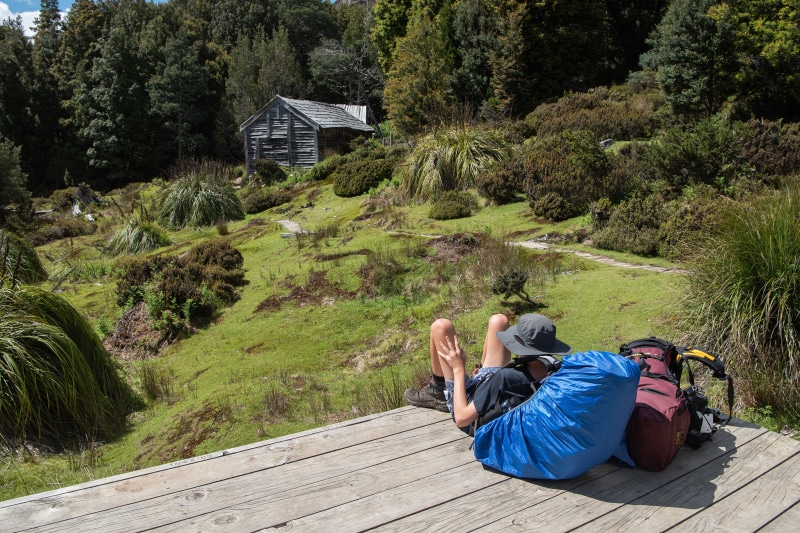 Backpacker resting near a rustic cabin in Tasmania, Australia