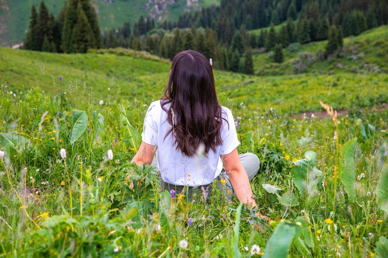 Woman sitting in a grassy field with trees in the background