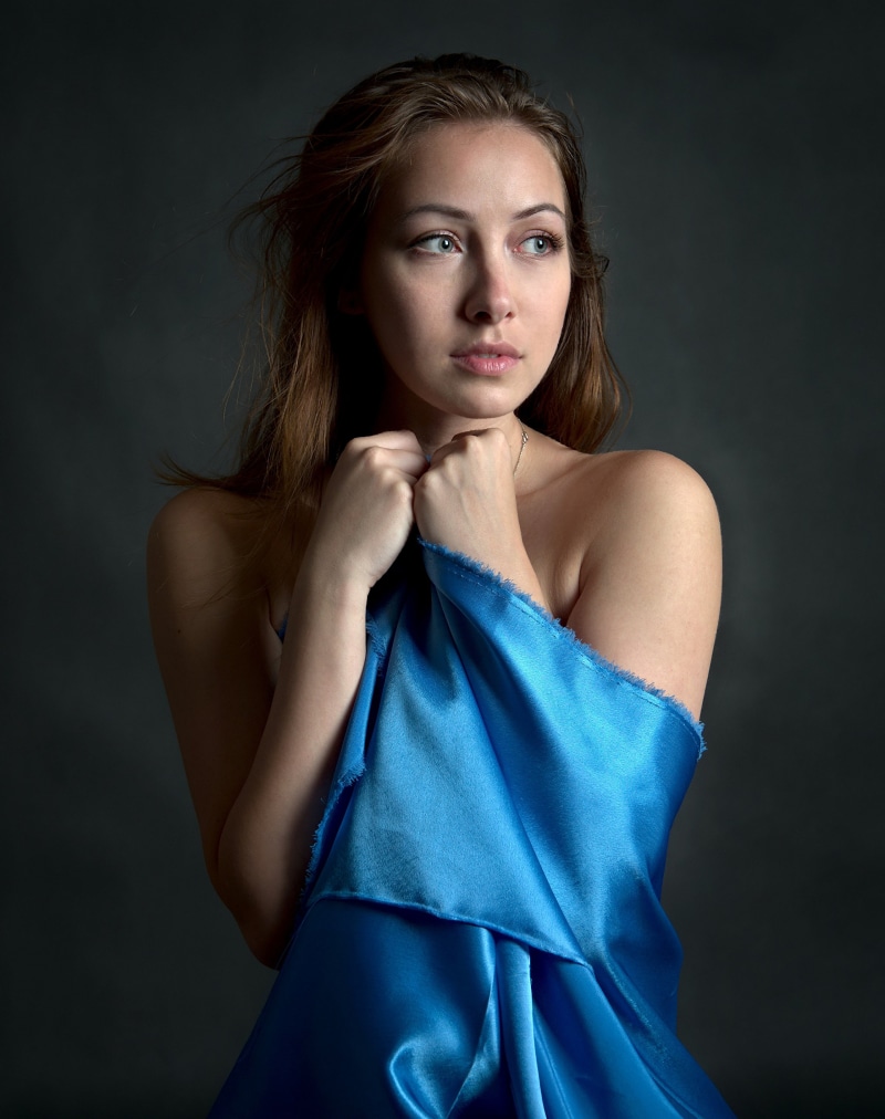 Woman draped in blue fabric looking away