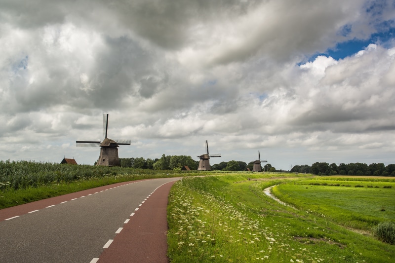 Four windmills on a cloudy day with a road