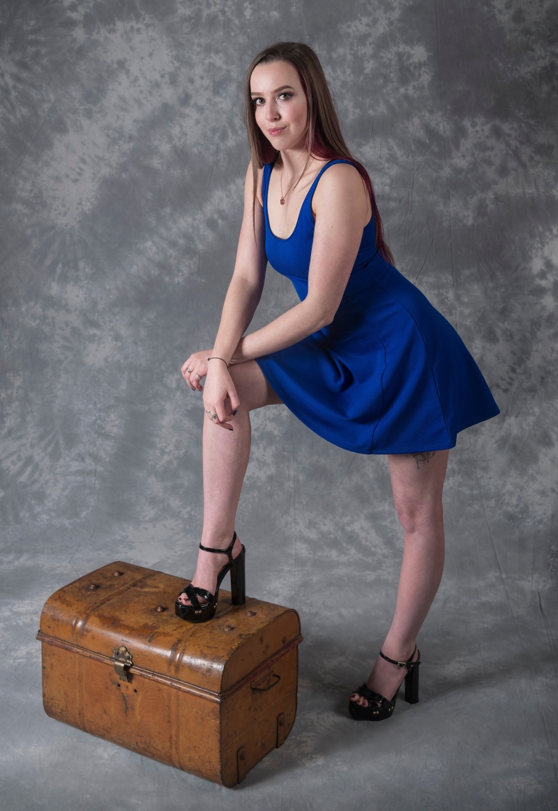 Woman in blue dress posing on a trunk