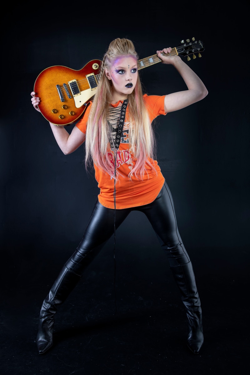 Mia with blonde hair holding a guitar