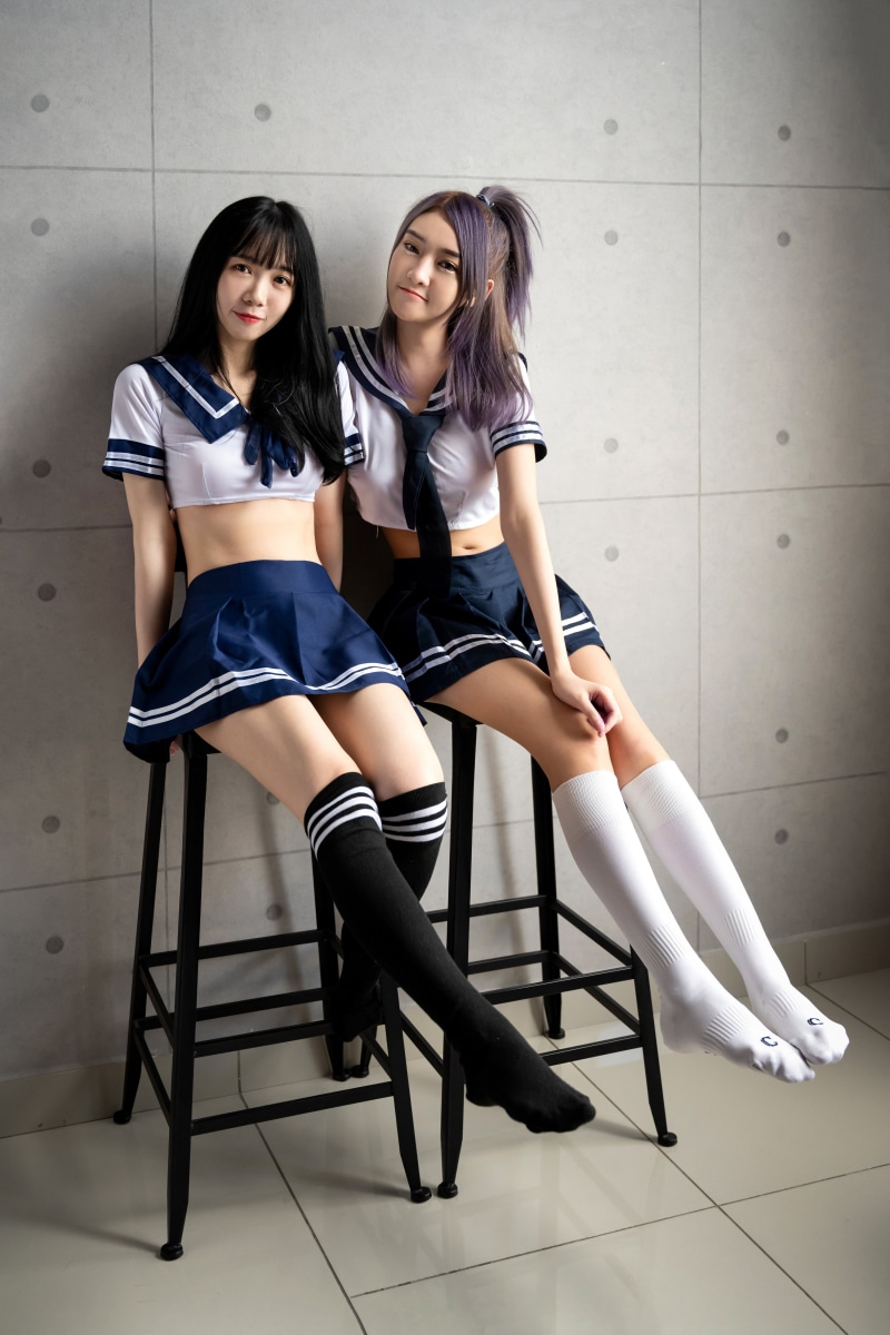 Two Asian schoolgirls in sailor uniforms and knee-high socks