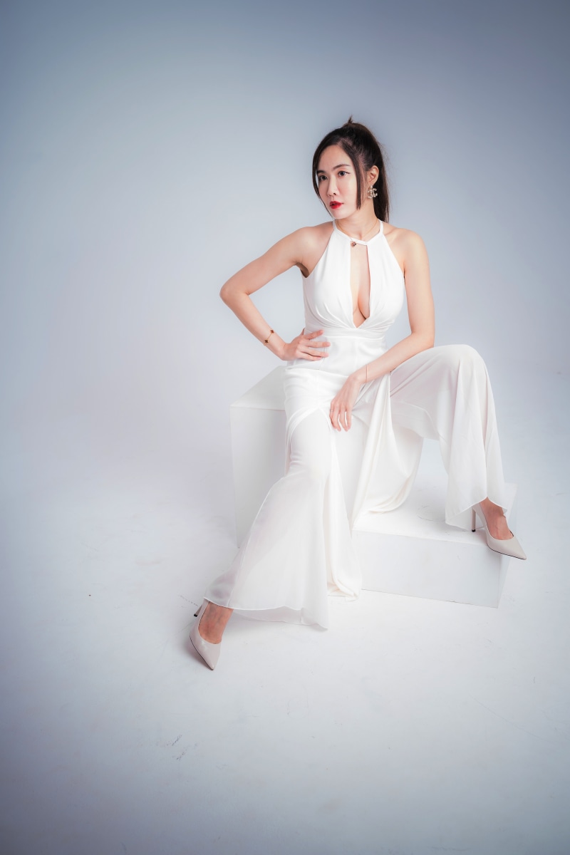 Asian woman in white dress posing on white cube