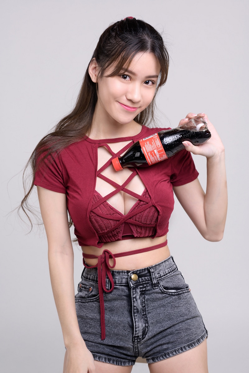 Asian woman in crop top holding Coca-Cola bottle