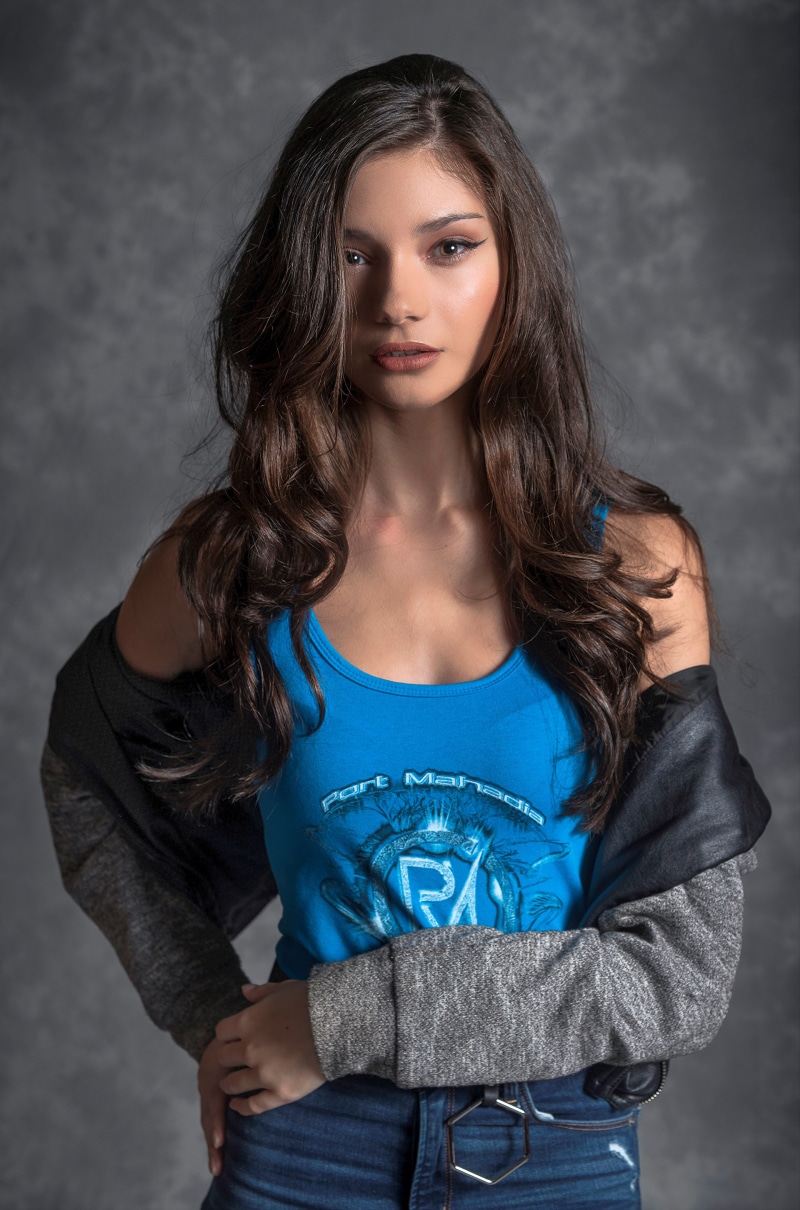 Brunette model wearing a blue singlet and denim jeans