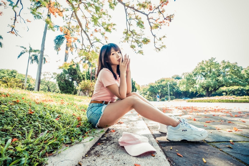 Asian woman sitting in park with athletic shoes