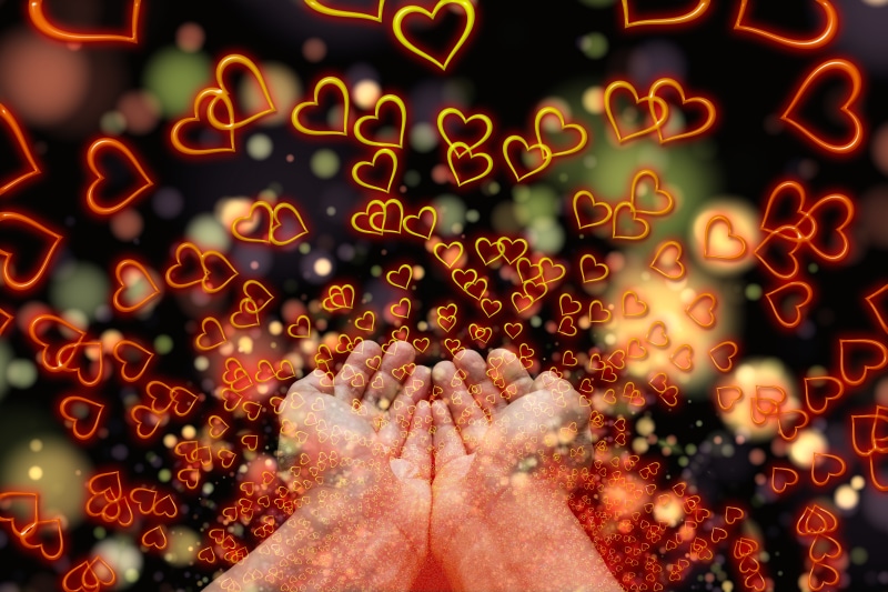 Hands releasing many glowing hearts