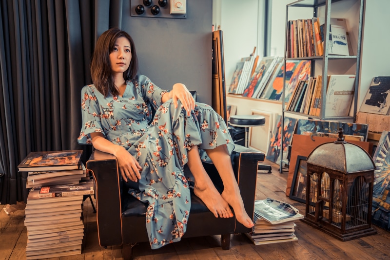 Asian woman in floral dress sitting in armchair