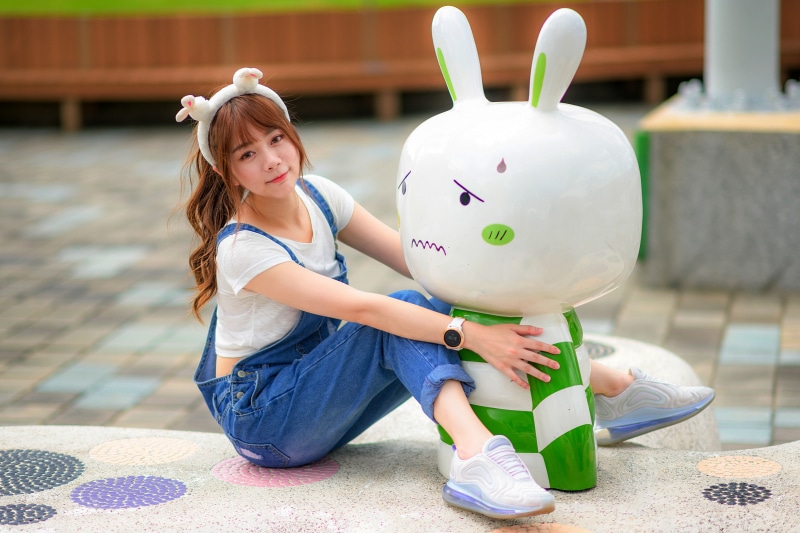 Asian girl in denim overalls with a cartoon rabbit statue