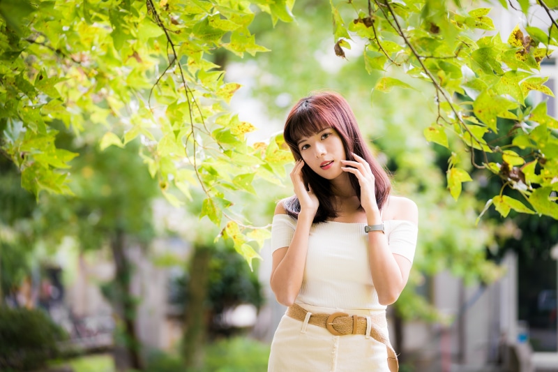 Asian woman posing under green branches