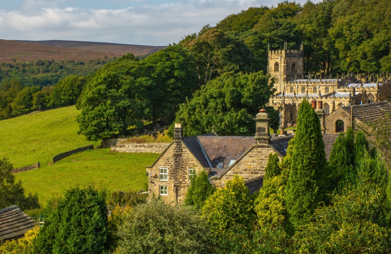 Church tower in High Bradfield, England with trees and hills