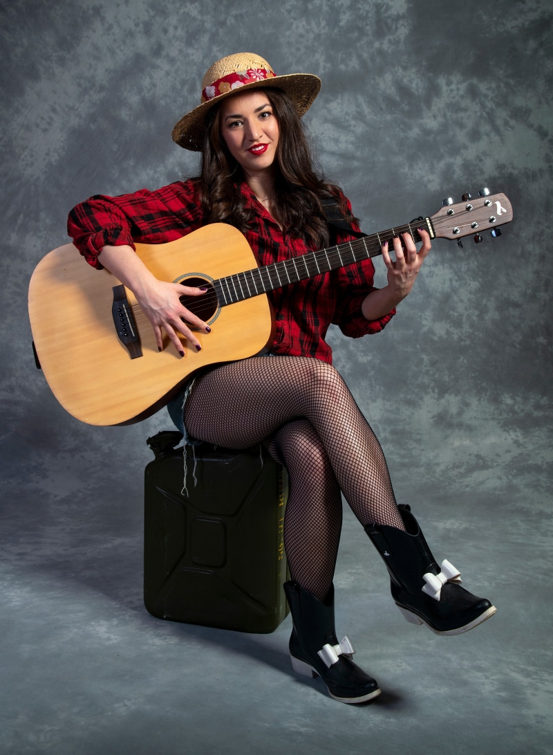 Catherine playing guitar while sitting on a jerrycan