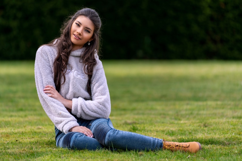 Model Sitting on Grass Wearing Sweater and Jeans
