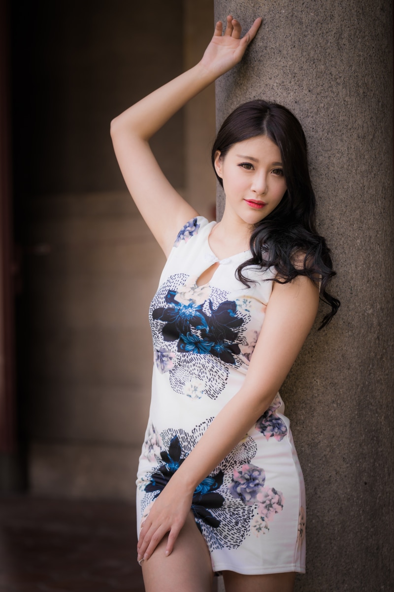 Asian woman in floral dress leaning on pillar