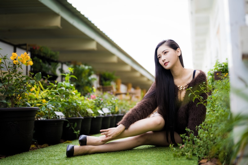 Asian woman sitting on grass with plants