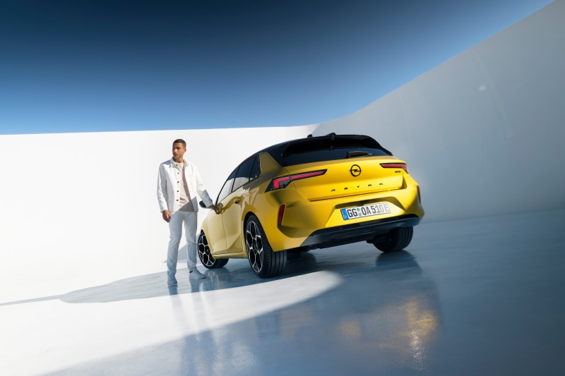 Man standing next to yellow Opel Astra Hybrid