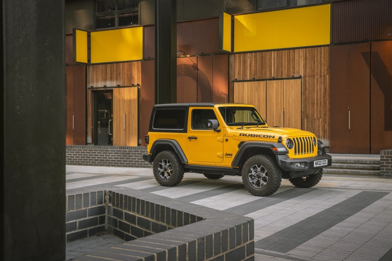 Yellow Jeep Wrangler Rubicon parked in front of a modern building